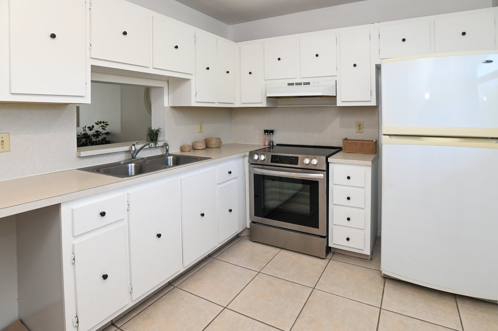 Kitchen with white cabinets, stainless steel range, and tile floor