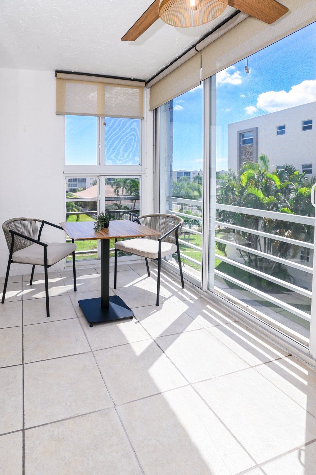 Screened-in balcony with a bistro table and views of the community grounds
