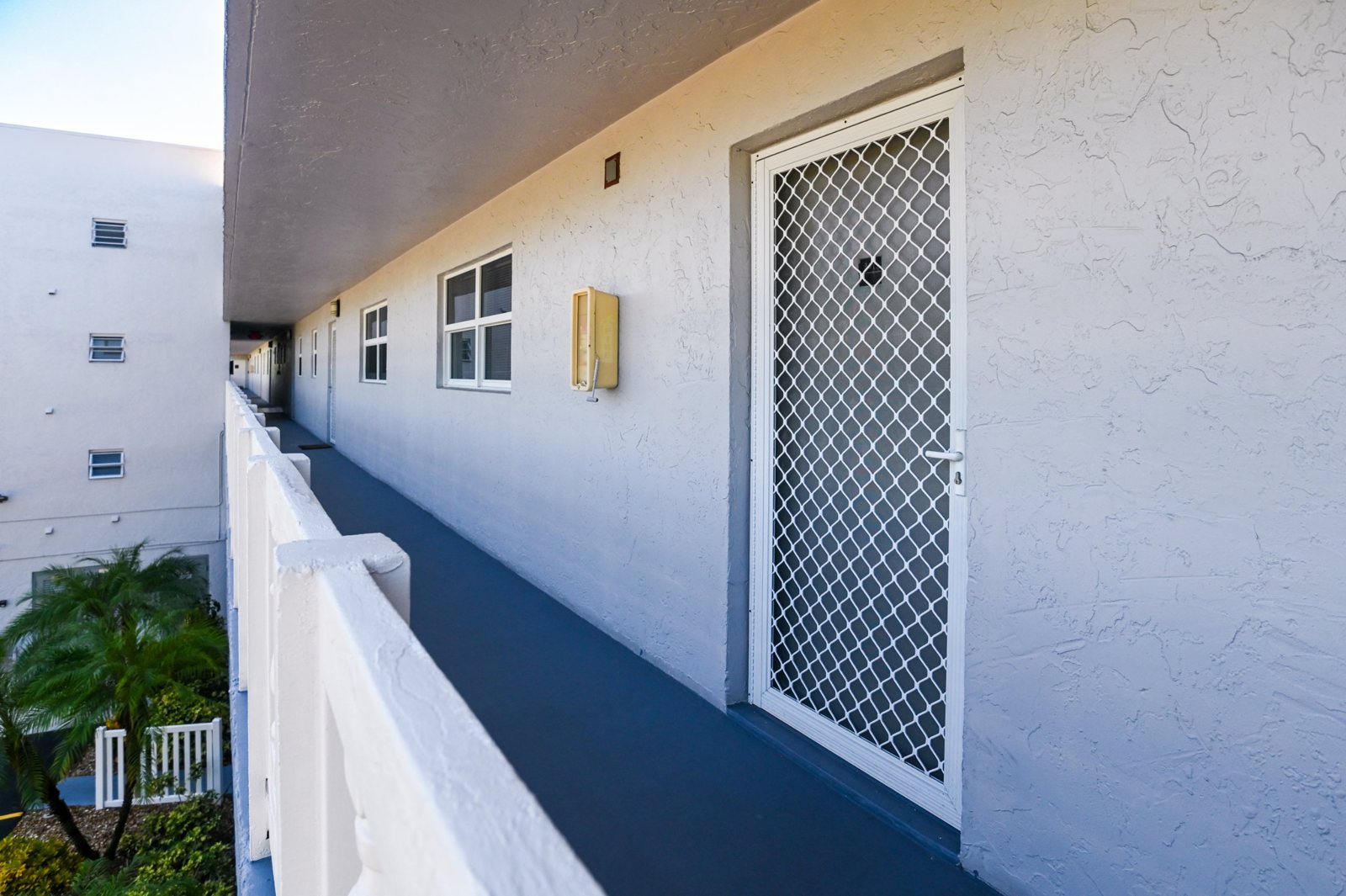 Covered walkway to the unit with a security screen door